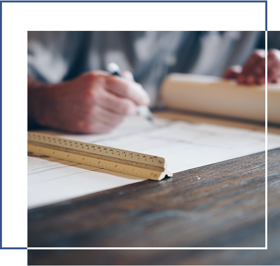 A person writing on paper with a ruler and pencil.