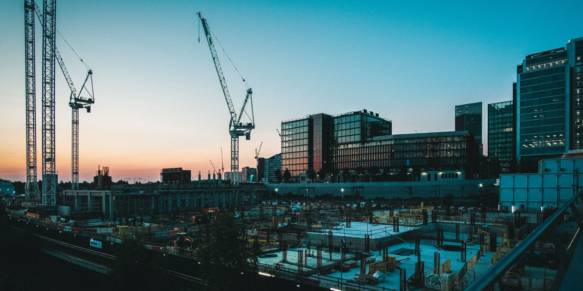 A construction site with cranes and buildings in the background.